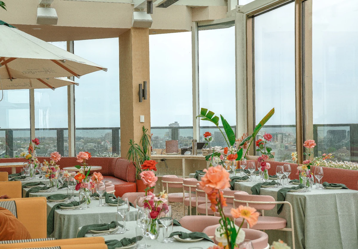 Colourful floral arrangements, green napkins and place settings on Beverly’s window-side dining tables