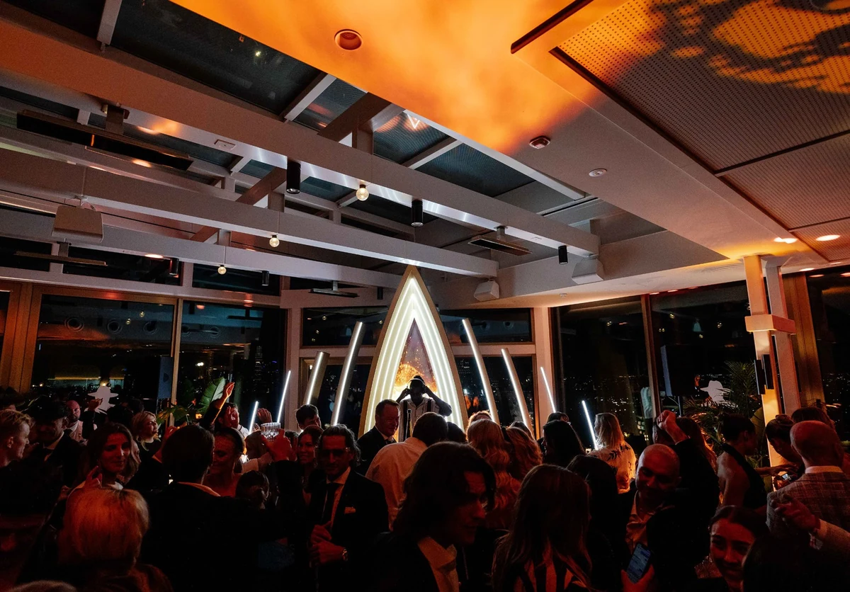 A crowd at an evening Beverly event with a DJ and illuminated installation