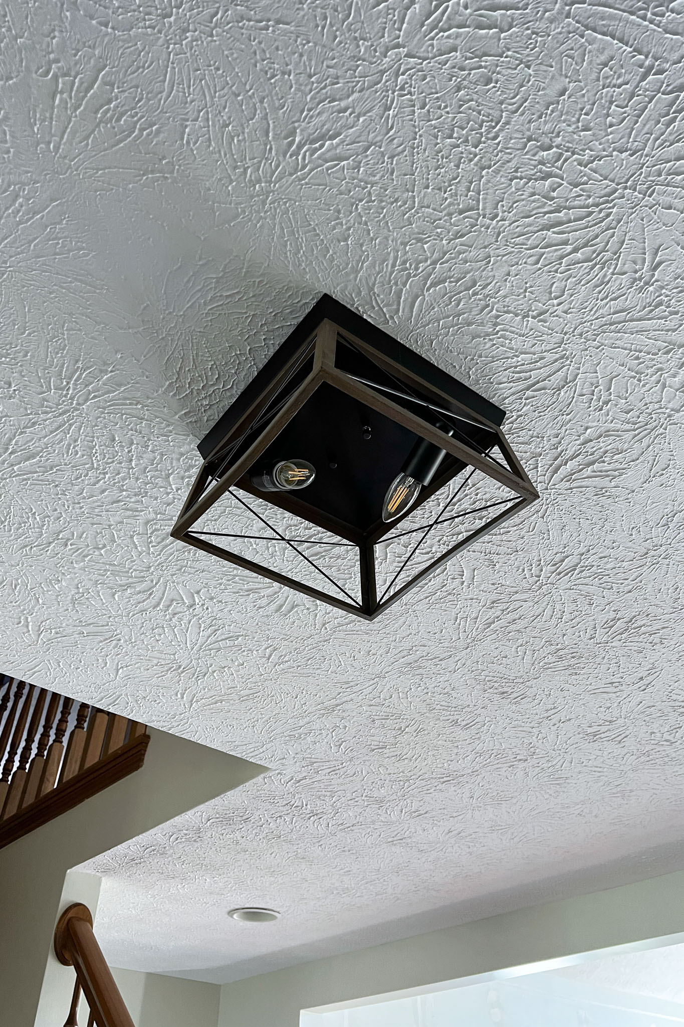A minimalist ceiling light fixture with a black metal frame.