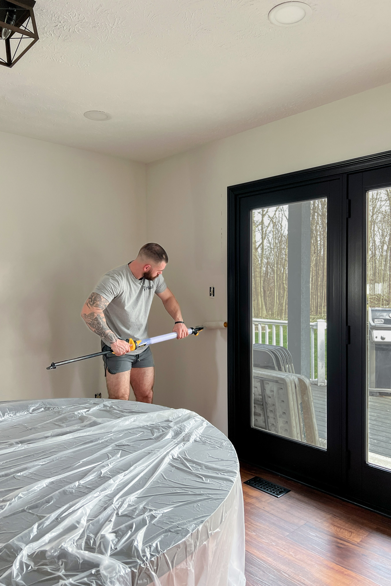 Christian with a paint roller painting the walls a light beige color.