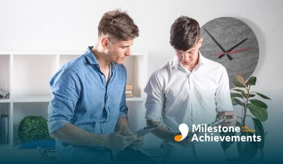 Two young ABA therapist in casual attire looking at a tablet and a tech circuit board with concentration.