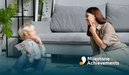 A child and therapist engaged in an interactive session, both smiling as they work together with educational cards.