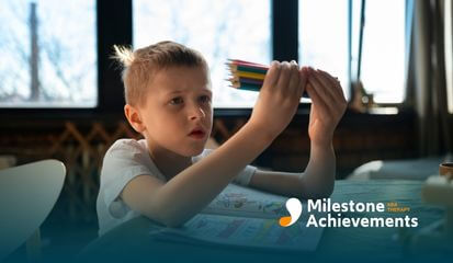 Autistic young boy studying a bunch of colored pencils, trying to decide which one to use next during ABA therapy.