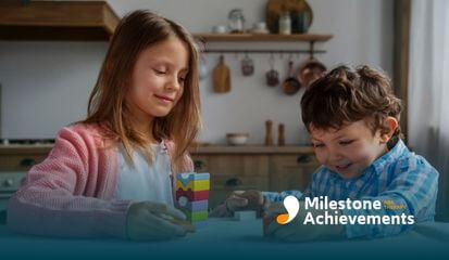 The autistic girl and autistic boy are smiling while playing with colorful blocks, engaging in cooperative play.