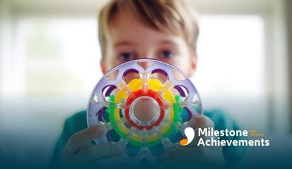 Child holding colorful sensory wheel toy close to face, symbolizing focus, sensory play, and autism-friendly learning tools