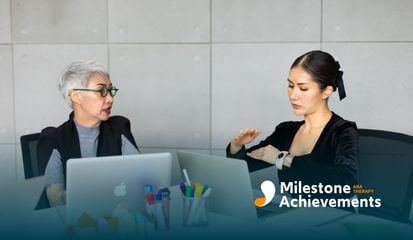 Two professionals collaborate at a table with laptops, discussing ideas and using hand gestures during a focused meeting.