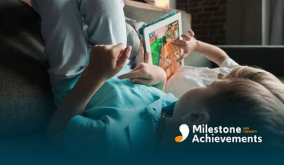 Child relaxes on a couch using a tablet game, illustrating screen-based engagement often addressed in social stories.