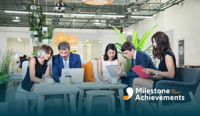 Team of professionals collaborates in a modern office lounge, reviewing documents and a laptop during a focused meeting.