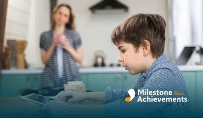 Child focused on tablet at kitchen table while caregiver stands nearby, showing screen time and supervision home.