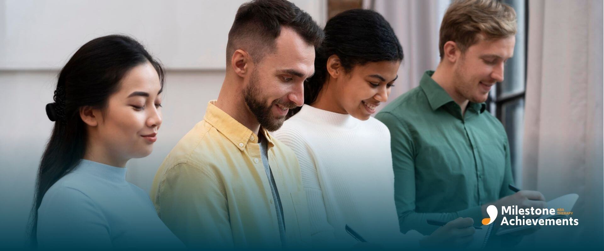 Four adult therapists standing side by side, writing in notebooks during a workshop or group training session.
