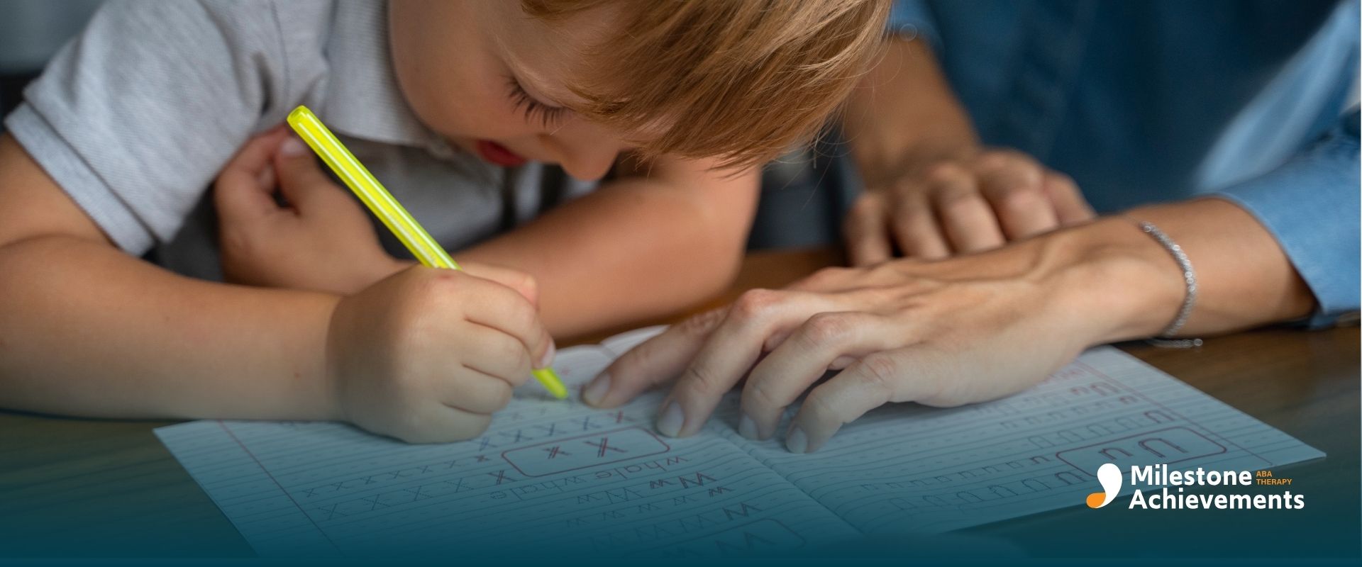 An ABA therapist helping an autistic boy practice handwriting with a pencil, supporting early writing development.