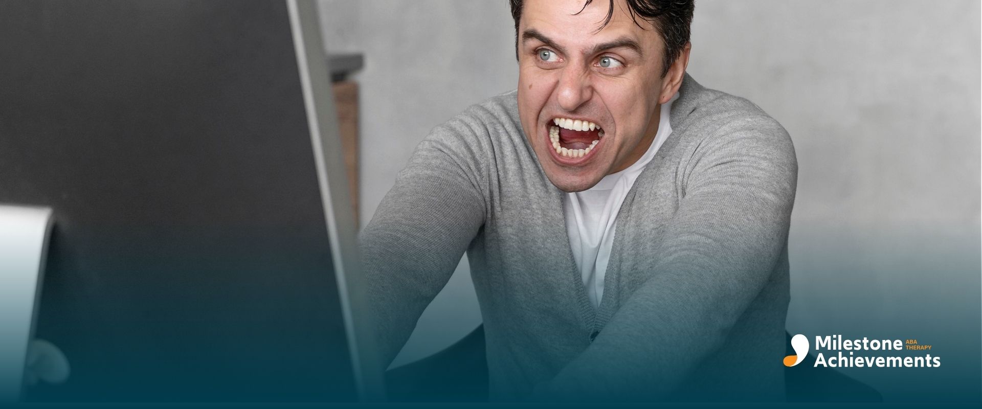 Frustrated autistic man shouting at a desktop computer while working at a desk, showing intense stress or anger during work