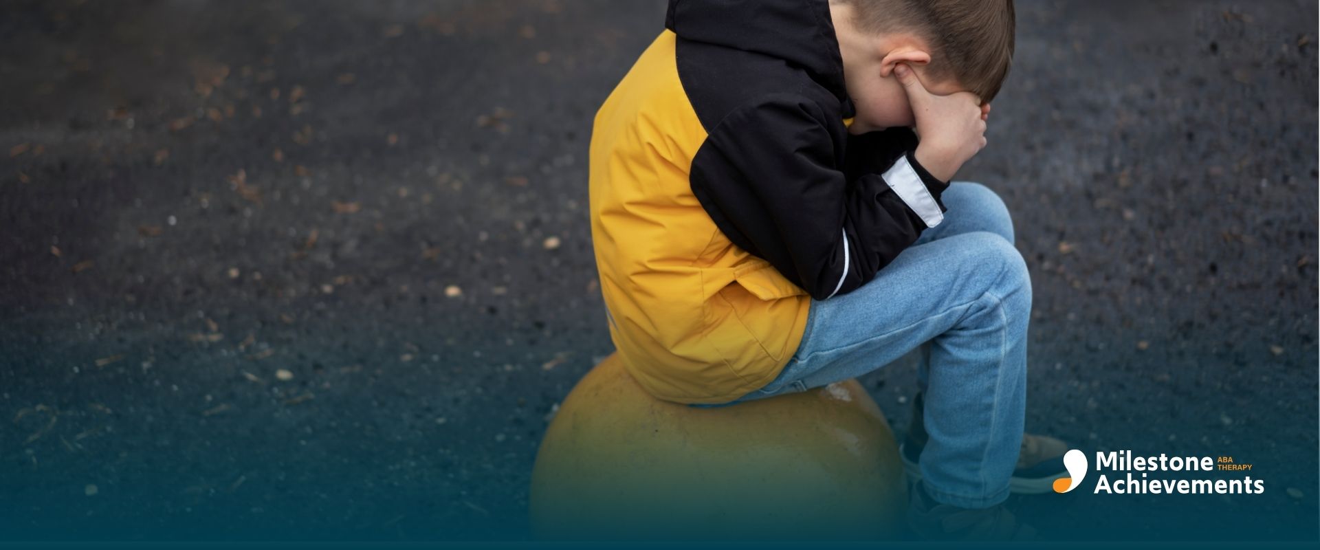 An autistic boy sits alone, head in hands, showing sadness and overwhelm linked to the autism grief cycle.