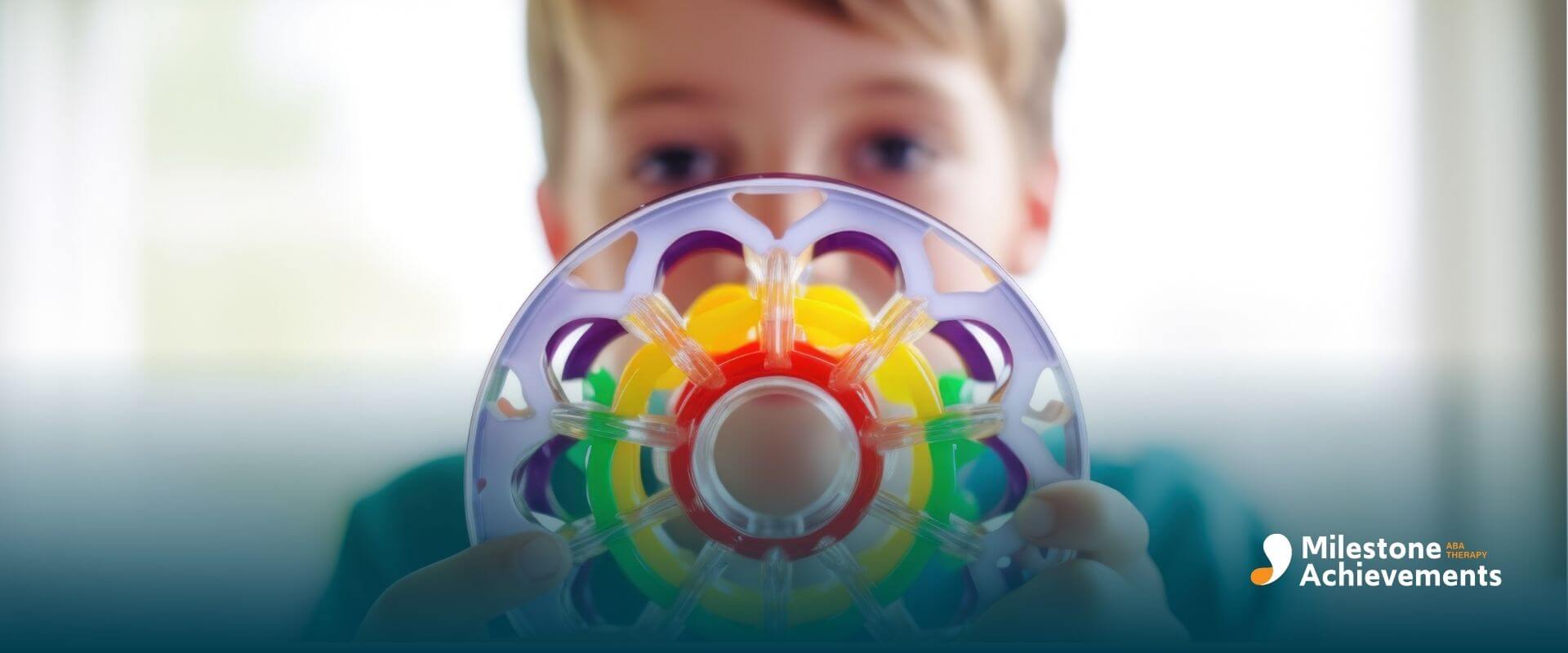 Autistic boy holding colorful circular sensory toy close to camera, highlighting fine motor skills and visual engagement.