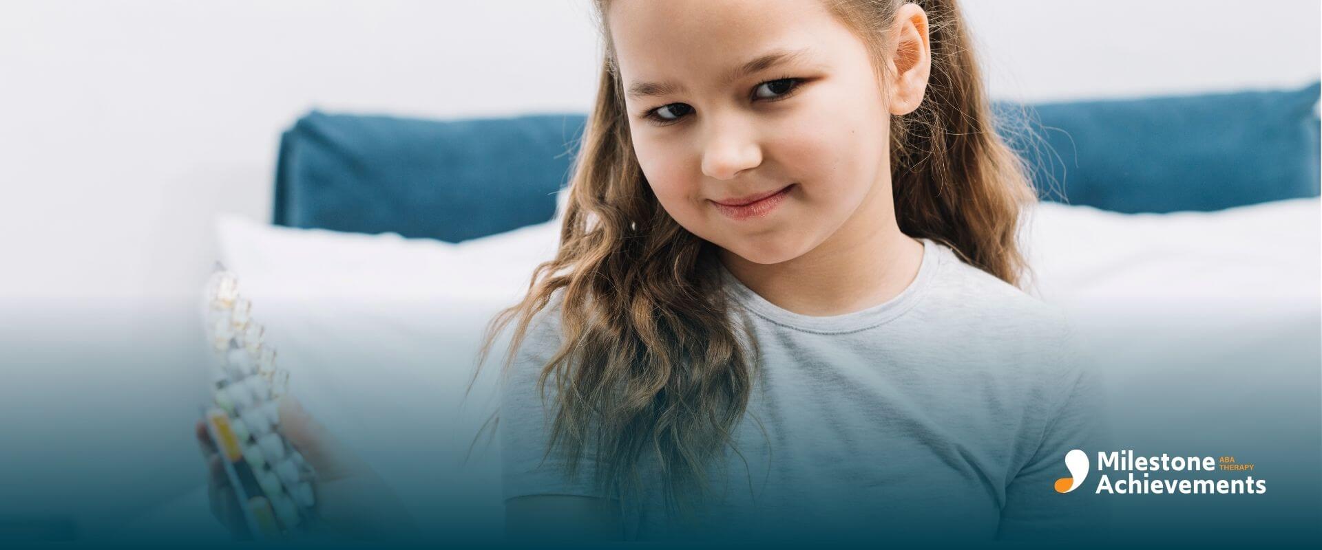 Autistic girl smiling in bedroom holding pill organizer, showing pediatric medication routine with adult supervision.