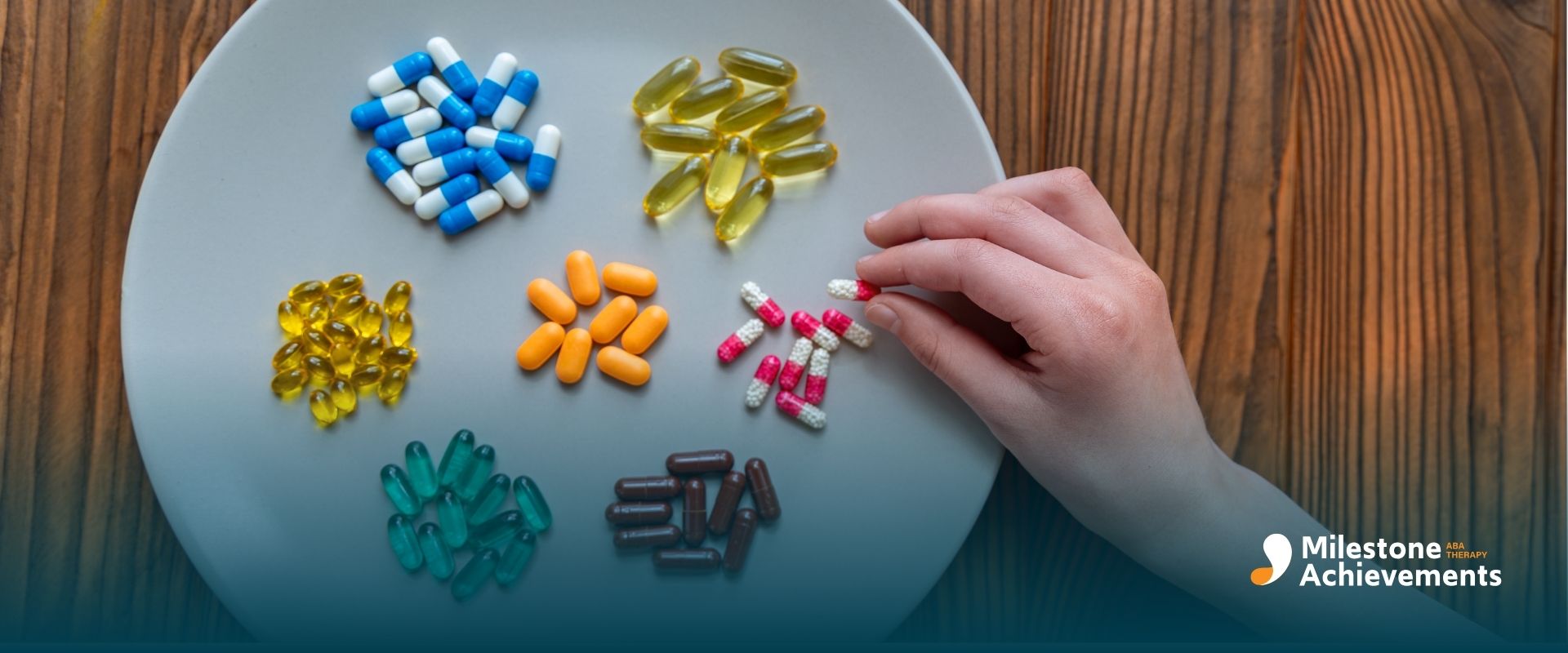 A hand of therapist reaching toward assorted colorful capsules and supplements arranged neatly on a plate.