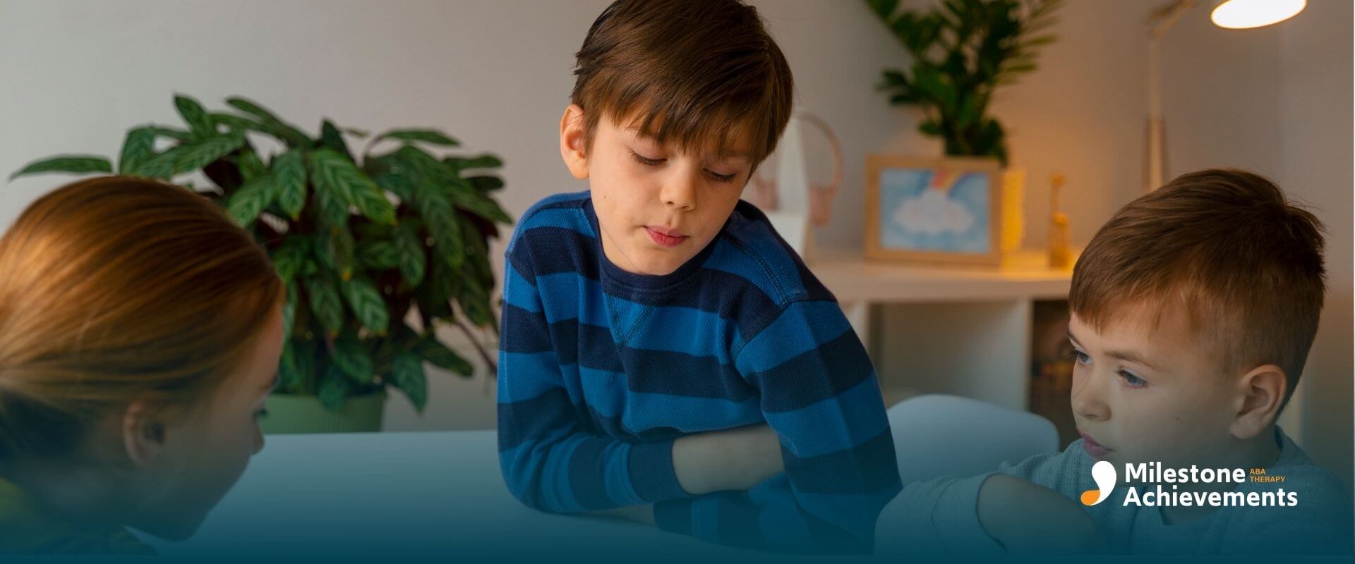 Autistic children sitting around a table playing a matching card game together during a social learning activity.