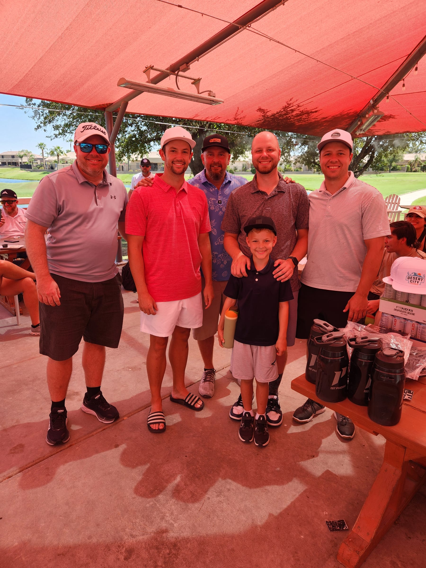 Five golfers and a young boy smiling together at the 2025 CrossFit Incite Golf Tournament