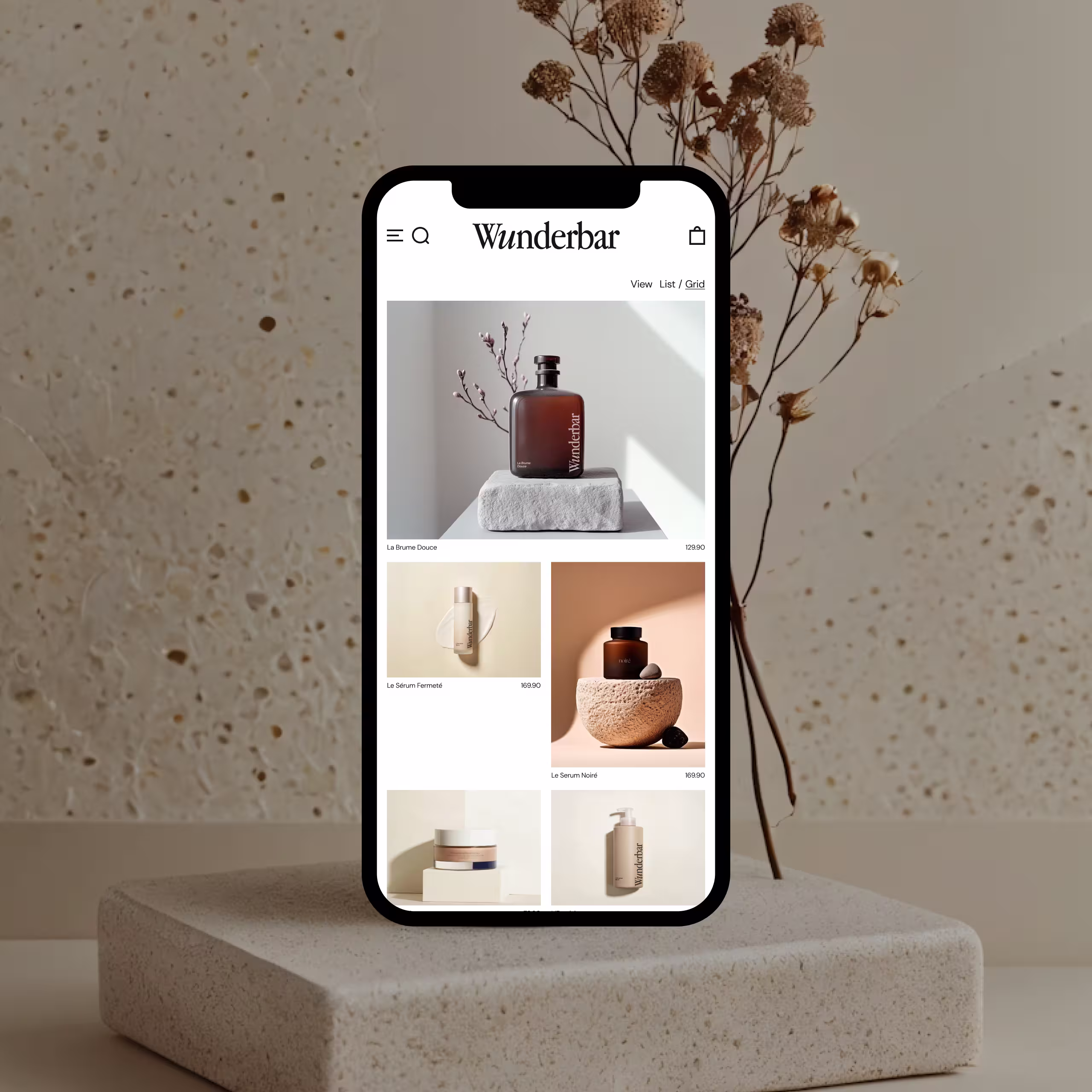 Mobile phone displaying Wunderbar skincare products with minimalist design on a textured stone pedestal and dried plants in the background.