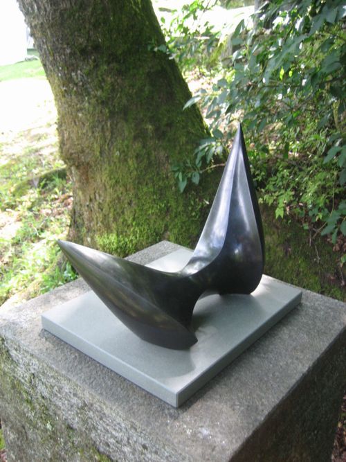 Spannungsvolle schwarze Steinskulptur von Pli Ebnöther mit zwei kraftvoll aufragenden Spitzen auf einem Steinsockel im Grünen – abstrakte Schweizer Kunst und zeitgenössische Bildhauerei aus Altstätten im St. Galler Rheintal und der Ostschweiz.