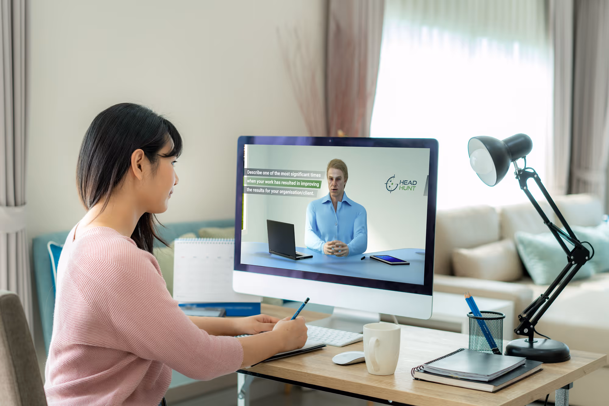 A woman completing her GoHeadHunt video introduction  at a desk, with the GoHeadHunt AI interviewer avatar  visible on her computer screen.
