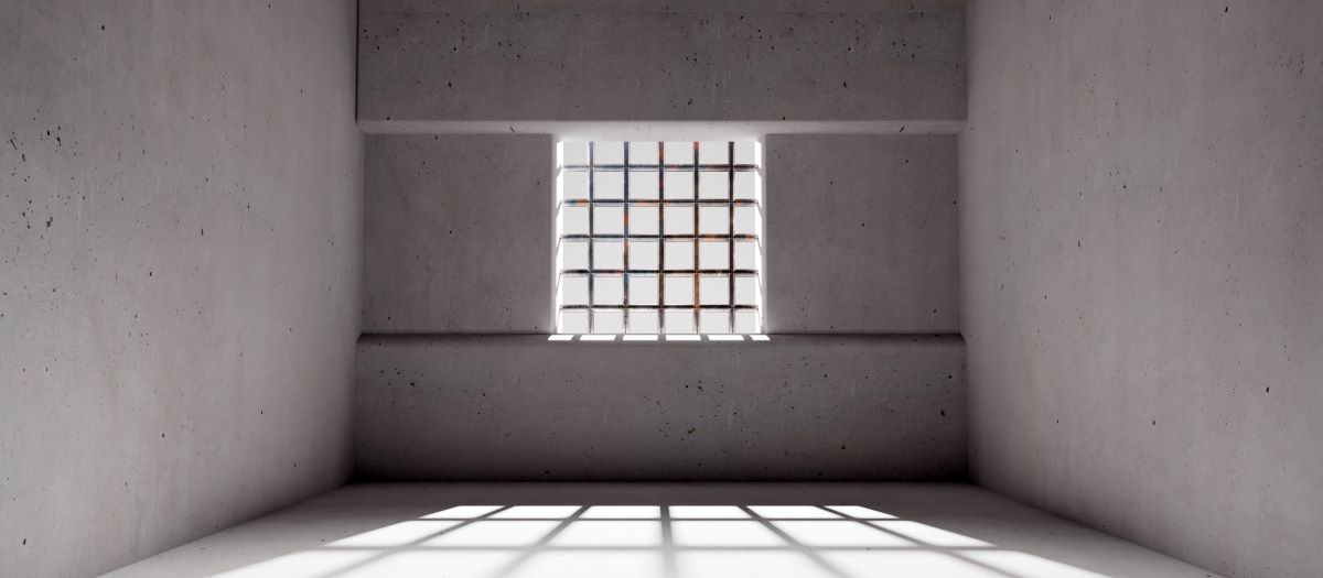Empty grey room with a window that is barred