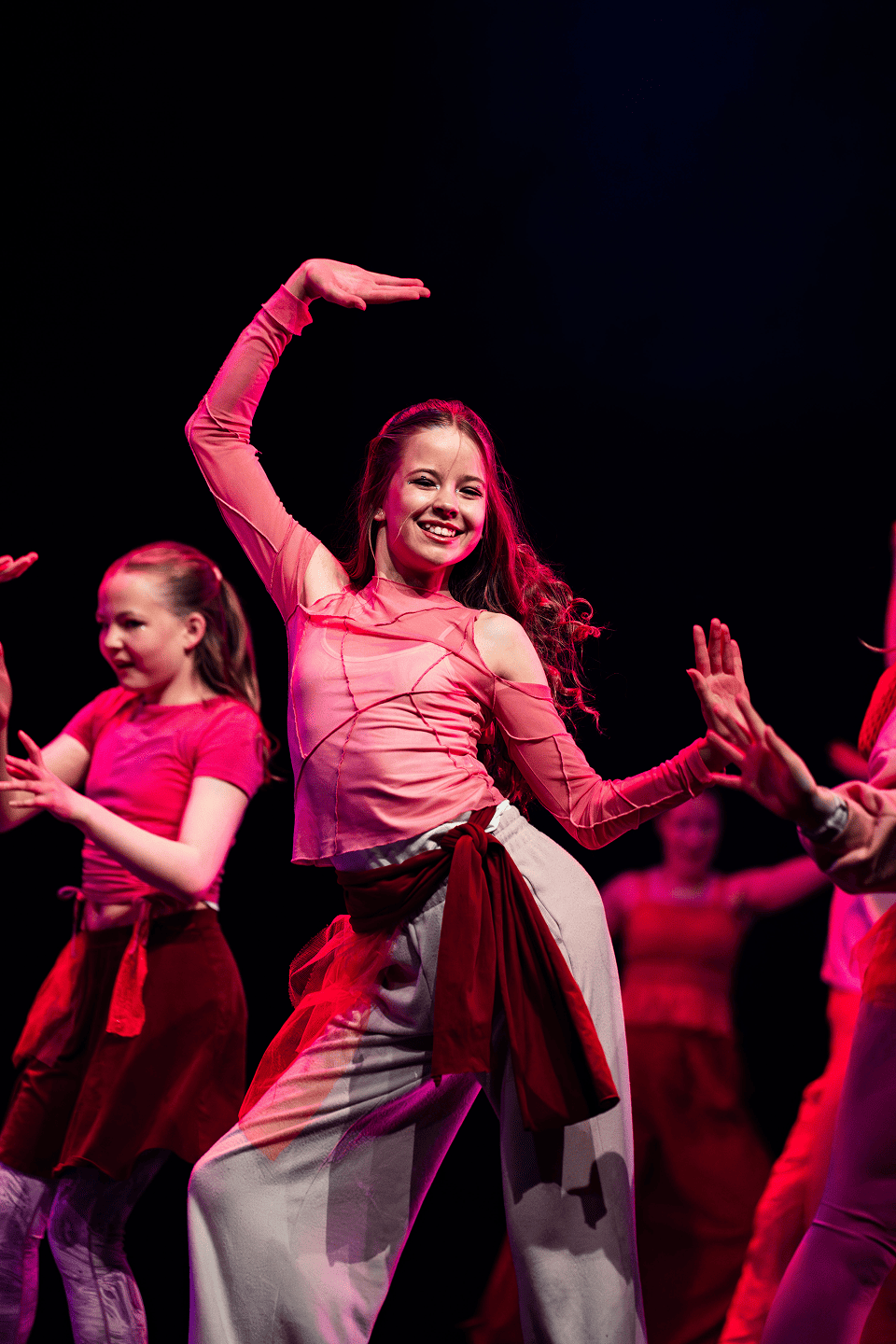 Dancers in a row with their hands up.