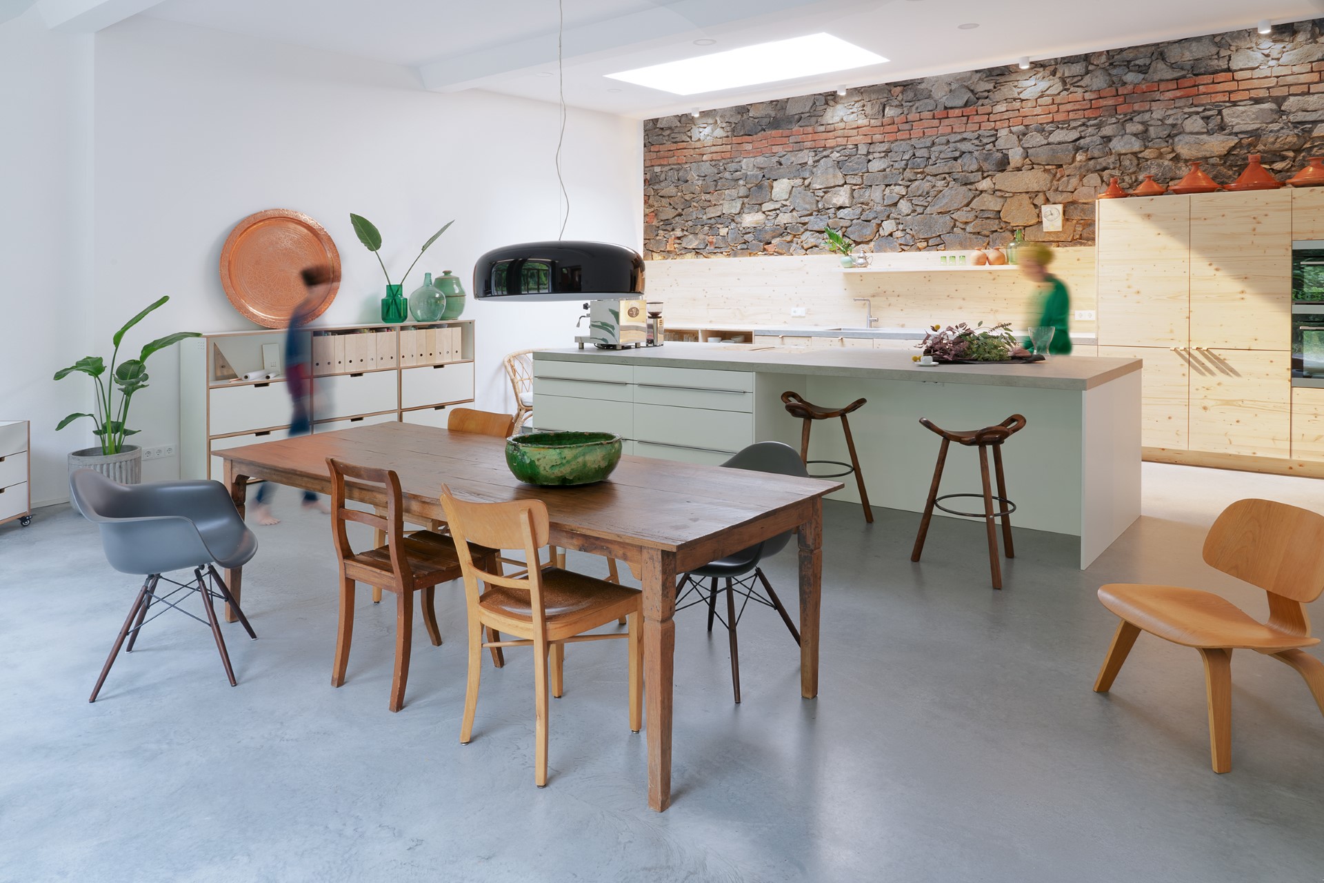 Heller Küchen- und Essbereich mit Natursteinwand, Holzoberflächen und Betonboden, Innenausbau in München