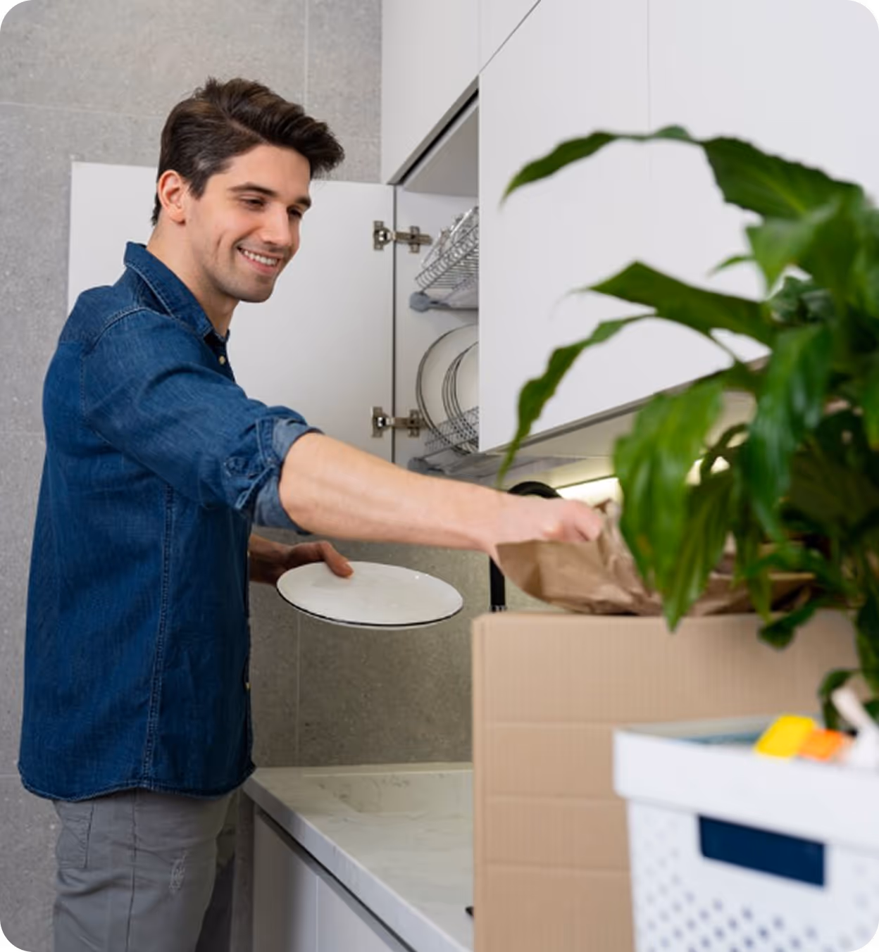 A man places a plate into a cardboard box, preparing it for storage or transport.