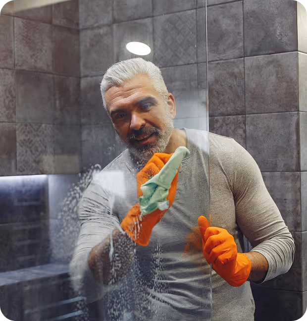 A man is vacuuming a tidy living room, focusing on the carpet while surrounded by furniture and decor.