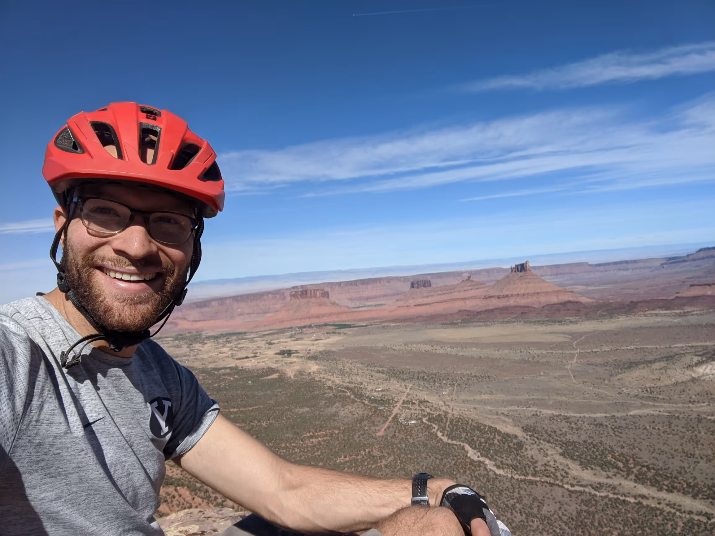 Dallin Farnsworth, an LVT employee, in a red bike helmet smiling in a scenic red rock landscape.