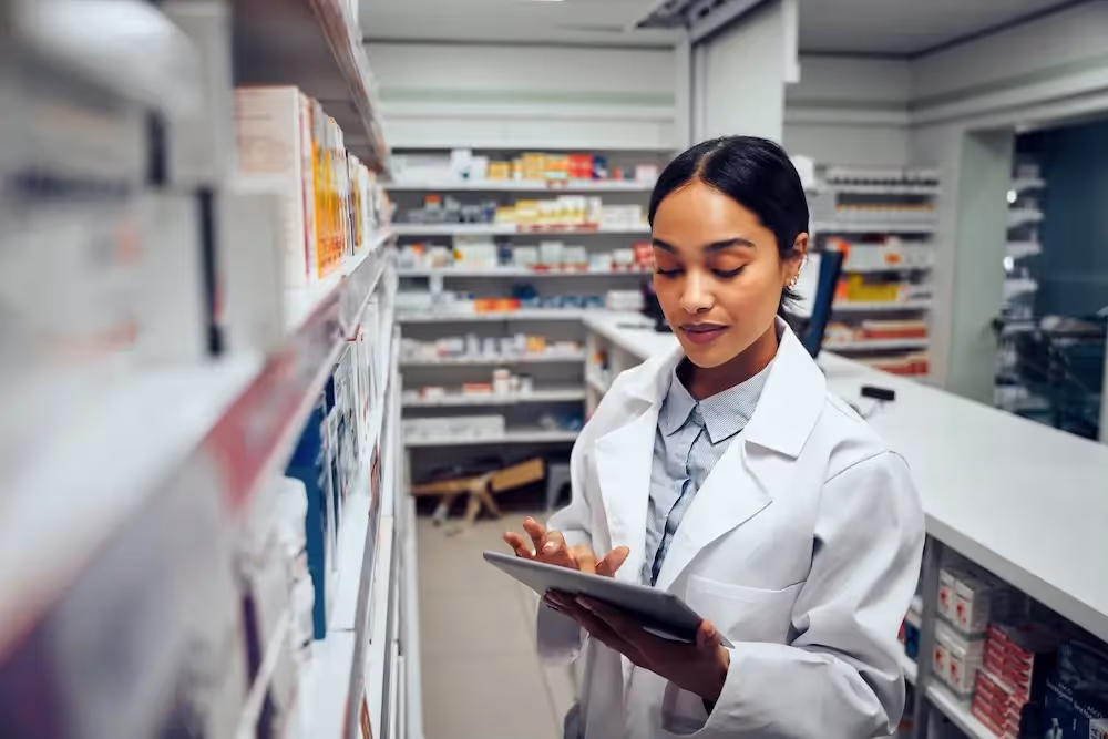 Female pharmacist using a tablet to take inventory.