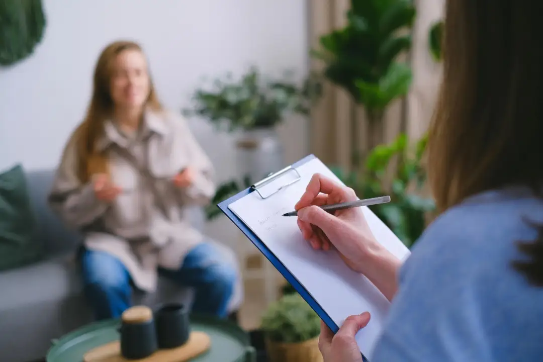 Thérapeute prenant des notes pendant une séance avec une cliente dans un cadre bien-être, illustrant l’importance du feedback client dans les accompagnements personnalisés.
