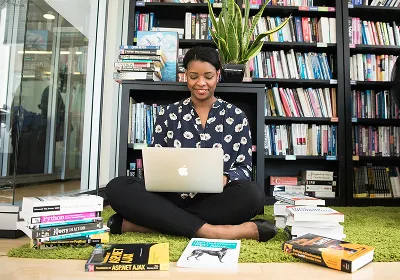 Une coach bien-être est représentée en train d'utiliser la plateforme Myndlee sur son ordinateur portable. L'écran suggère qu'elle est en train de créer des programmes en ligne ou des méditations guidées, afin de diversifier ses revenus en tant que coach bien-être ou de développement personnel.