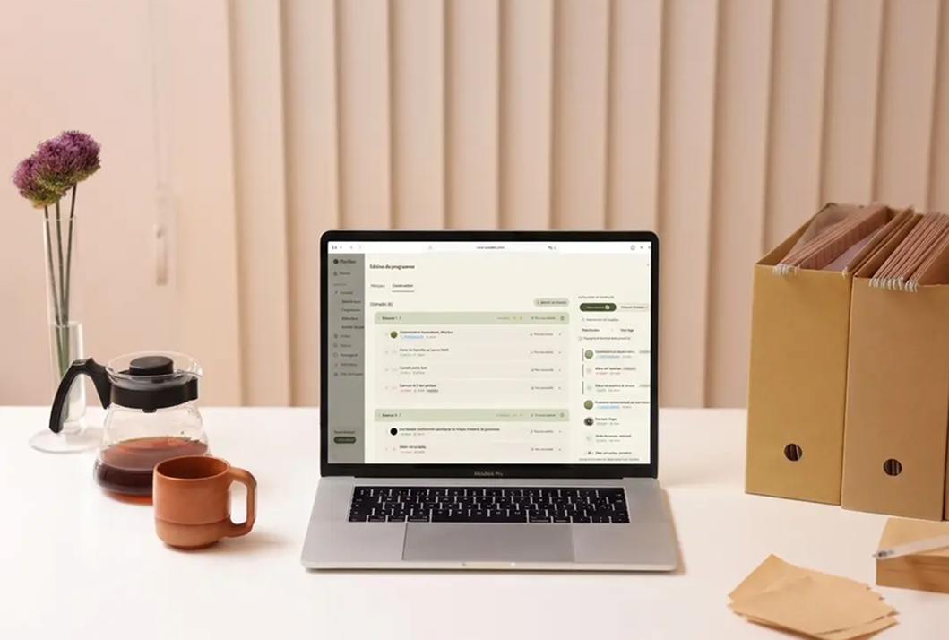Application Myndlee d'espace client pour praticien bien-être affichée sur un ordinateur portable dans un cabinet de thérapie organisé.