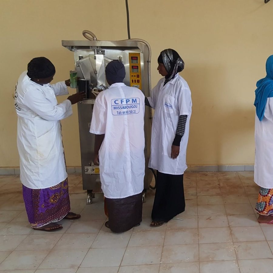 Apprenantes en blouse CFPM Missabougou autour d'une machine de conditionnement