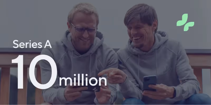 Zwei Männer in Hoodies lächeln, während sie Smartphones benutzen und eine Finanzierungsrunde über 10 Millionen Dollar feiern.