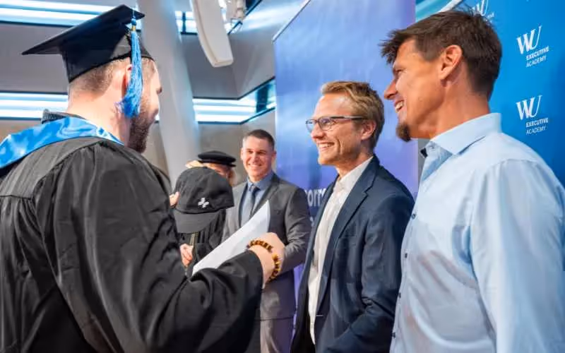 Graduate receiving diploma while shaking hands with Tomorrow University leaders