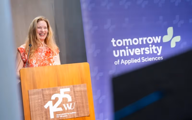 Smiling speaker addresses graduates from a Tomorrow University podium.