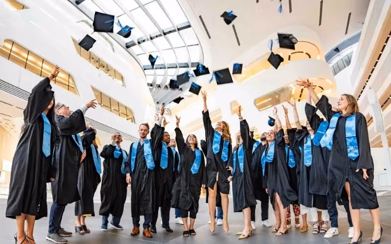 Graduates tossing caps in the air inside a modern building during their celebration