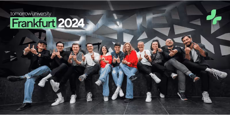 Gruppe von Tomorrow University Teammitgliedern in einer Reihe bei Frankfurt 2024, lächelnd und mit Daumen hoch.