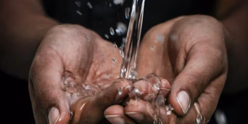 Hands cupped under flowing water, symbolizing access to clean water.