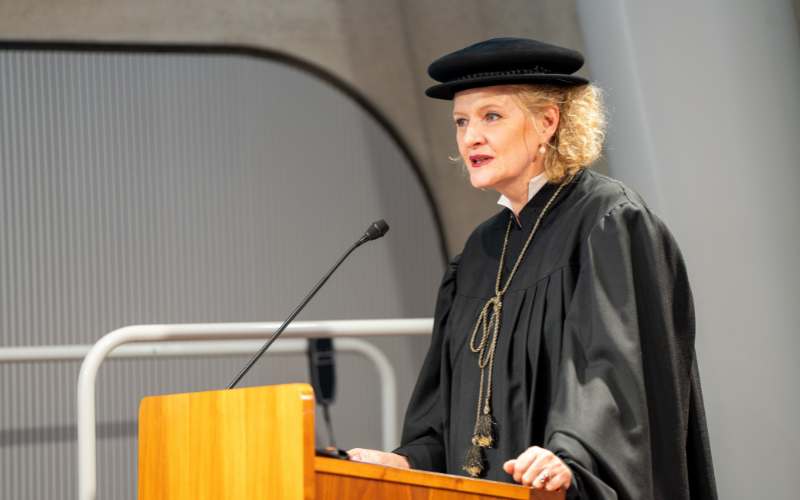 Dozenten im Talar hält Rede am Rednerpult.