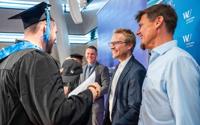 Absolvent erhält Diplom und schüttelt den Führern der Tomorrow University die Hand.