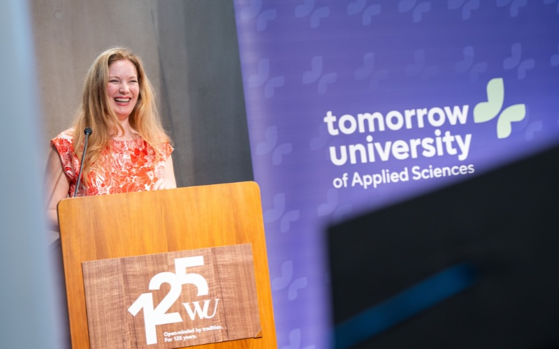 Lächelnde Rednerin spricht Absolventen von einem Tomorrow University Pult an.