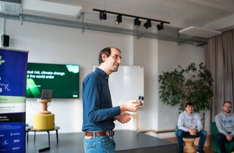 Nathan Bonnisseau spricht auf einer Veranstaltung, während Teilnehmende von ihren Plätzen aus zusehen.