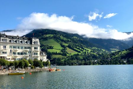 Seeblick mit historischem Hotel und grünem Bergpanorama in Zell am See, Österreich