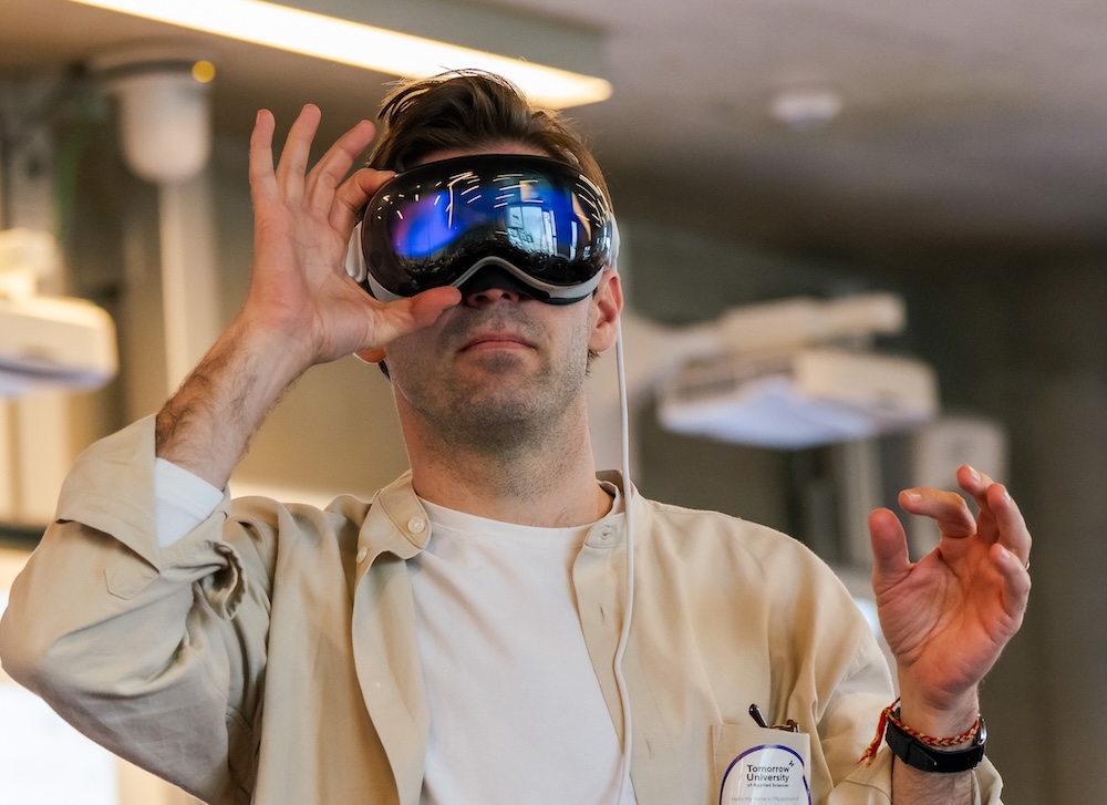 Person wearing a virtual reality headset indoors, holding one hand up as if interacting with a virtual environment.
