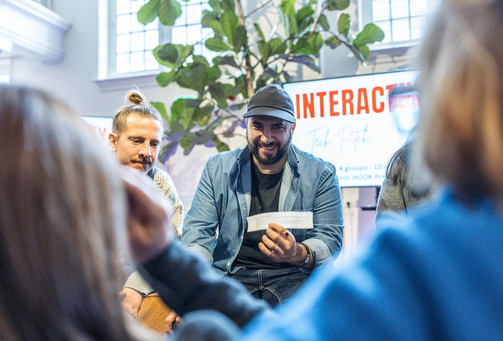 People seated in a circle during an interactive workshop, one participant holding a card while speaking to the group.