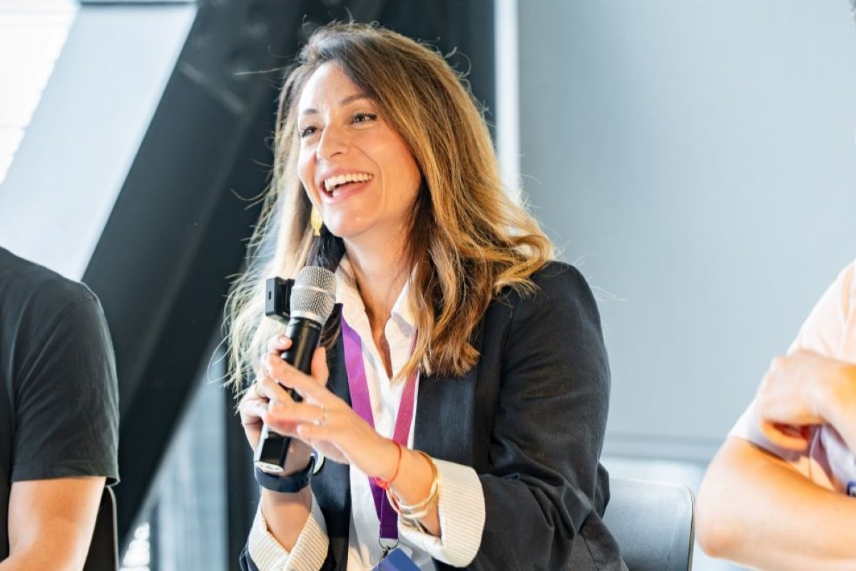 Roberta Scrofani laughs during a panel discussion, microphone in hand